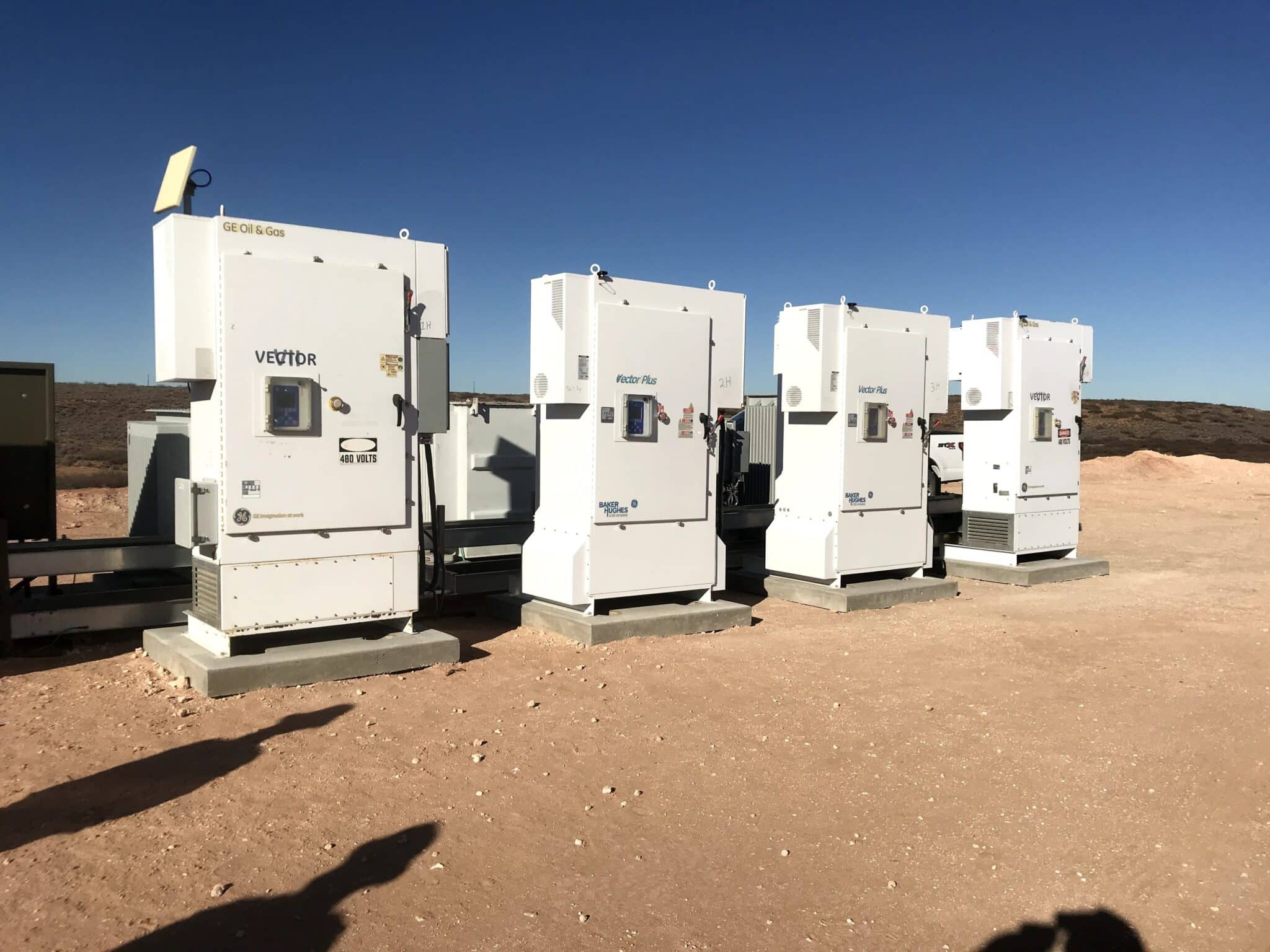 Four white electrical boxes installed outside on a sunny day