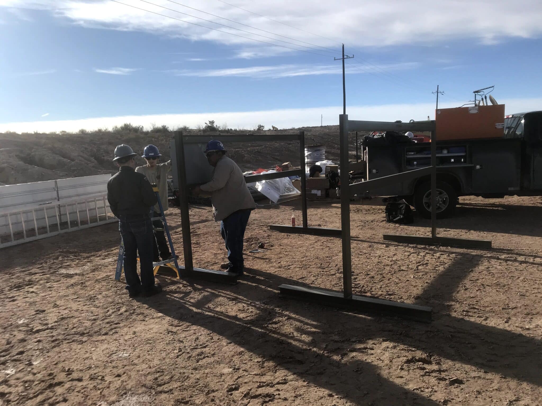 Three men installing large welded bars on job site