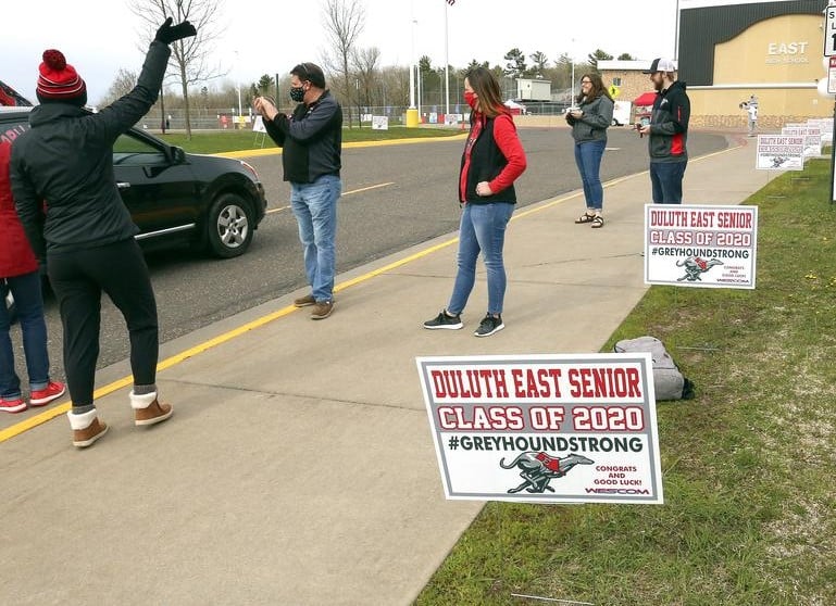 Wescom "Class of 2020' signs lining sidewalk with many people waving