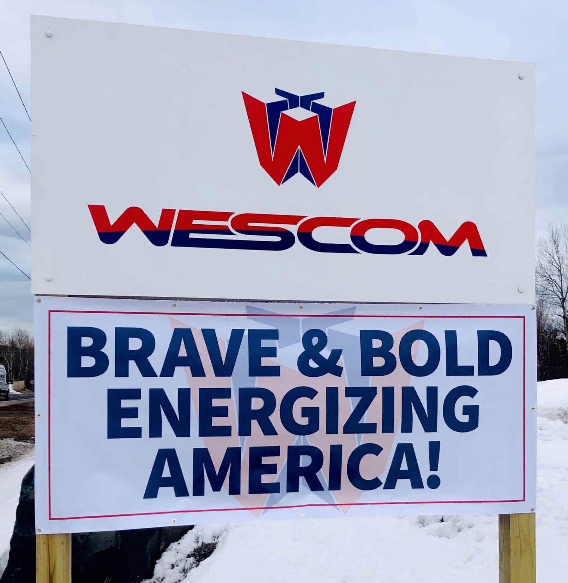 'Wescom Brave & Bold Energizing America' sign outside jobsite in snow