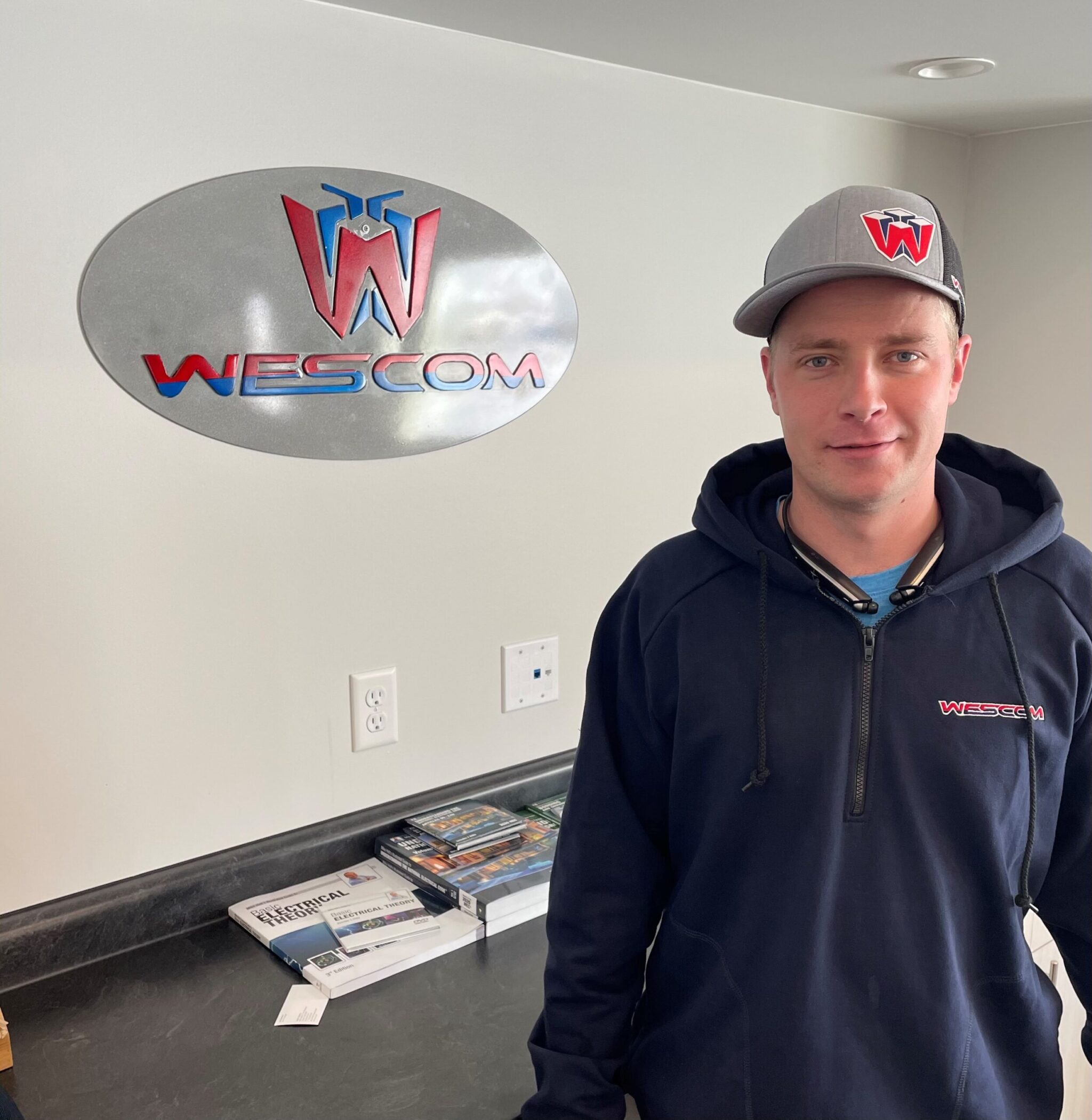 Cory Aili in front of wescom logo with wescom hat and shirt on