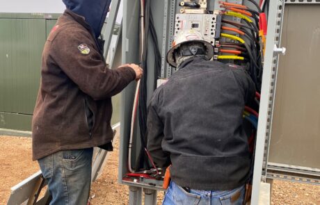 Two men hooking up an electrical panel