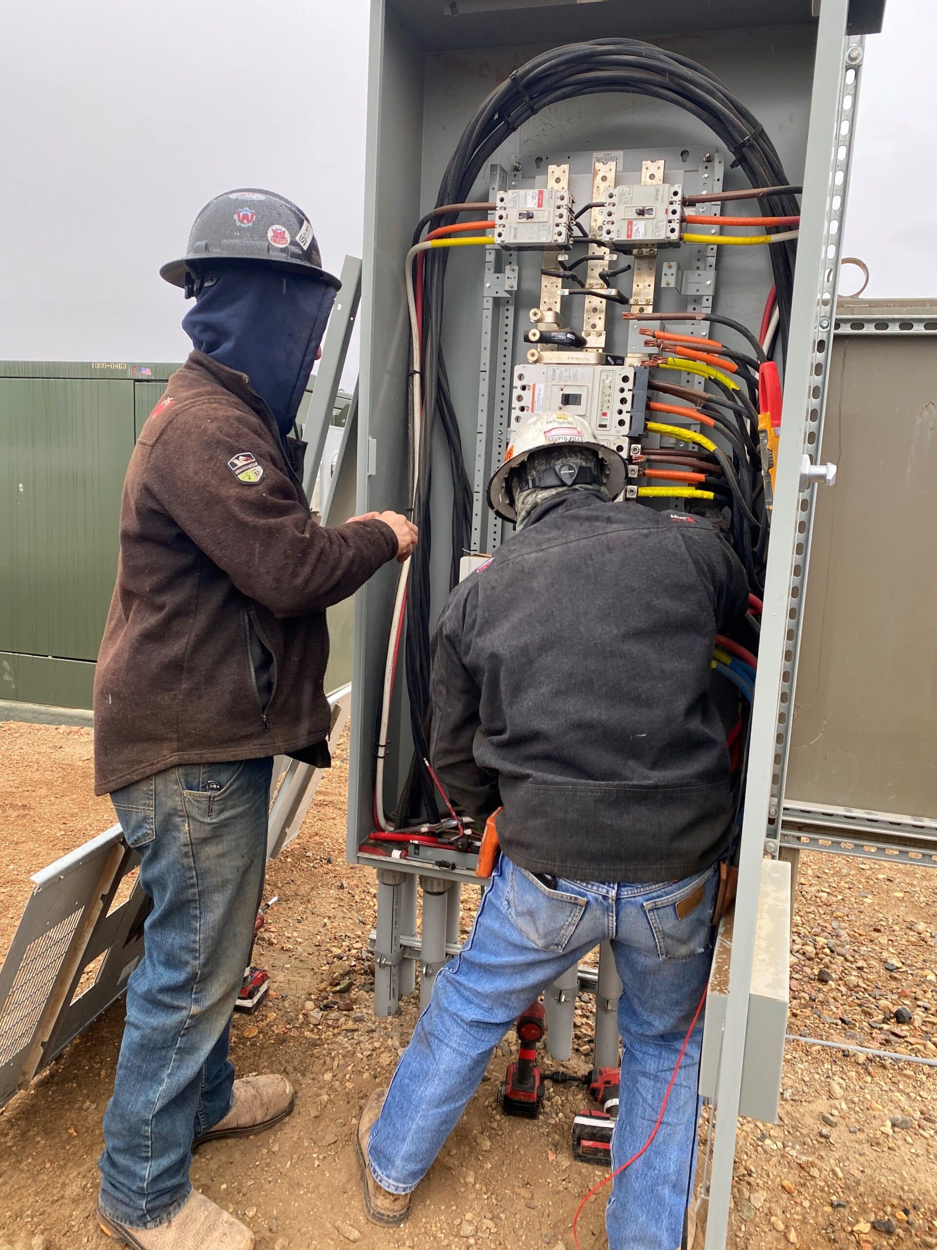 Two men hooking up an electrical panel