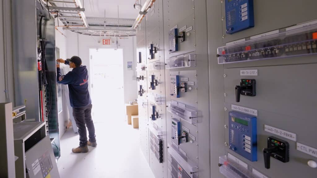 A man working on the electrical panels inside of a electrical building for a client