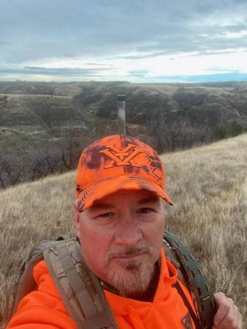 Russ Thomas (one of the veterans mentioned in the blog post) in orange gear with North Dakota scenery in the background.