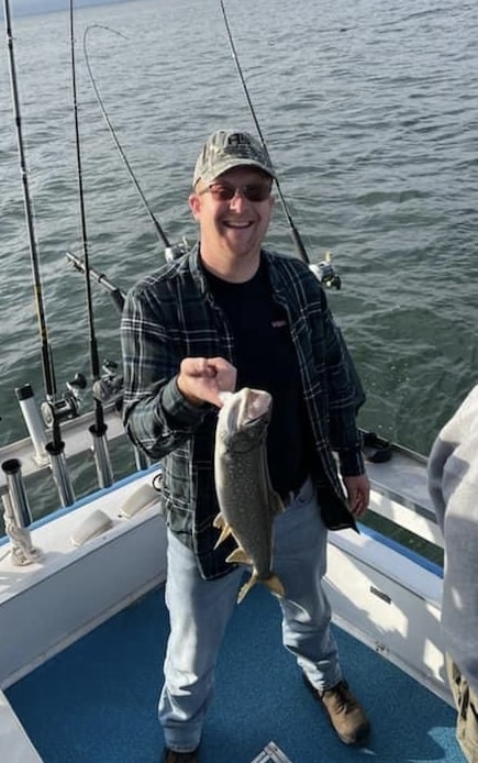 Smiling man holding a fish on a boat