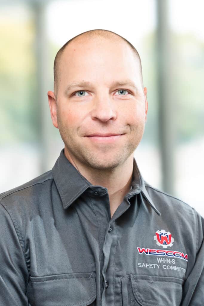 Smiling Wescom employee wearing gray shirt