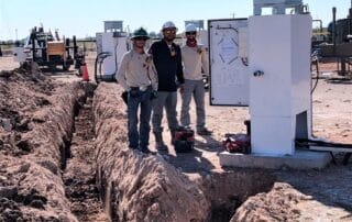 Men standing by electrical box next to wire pull.