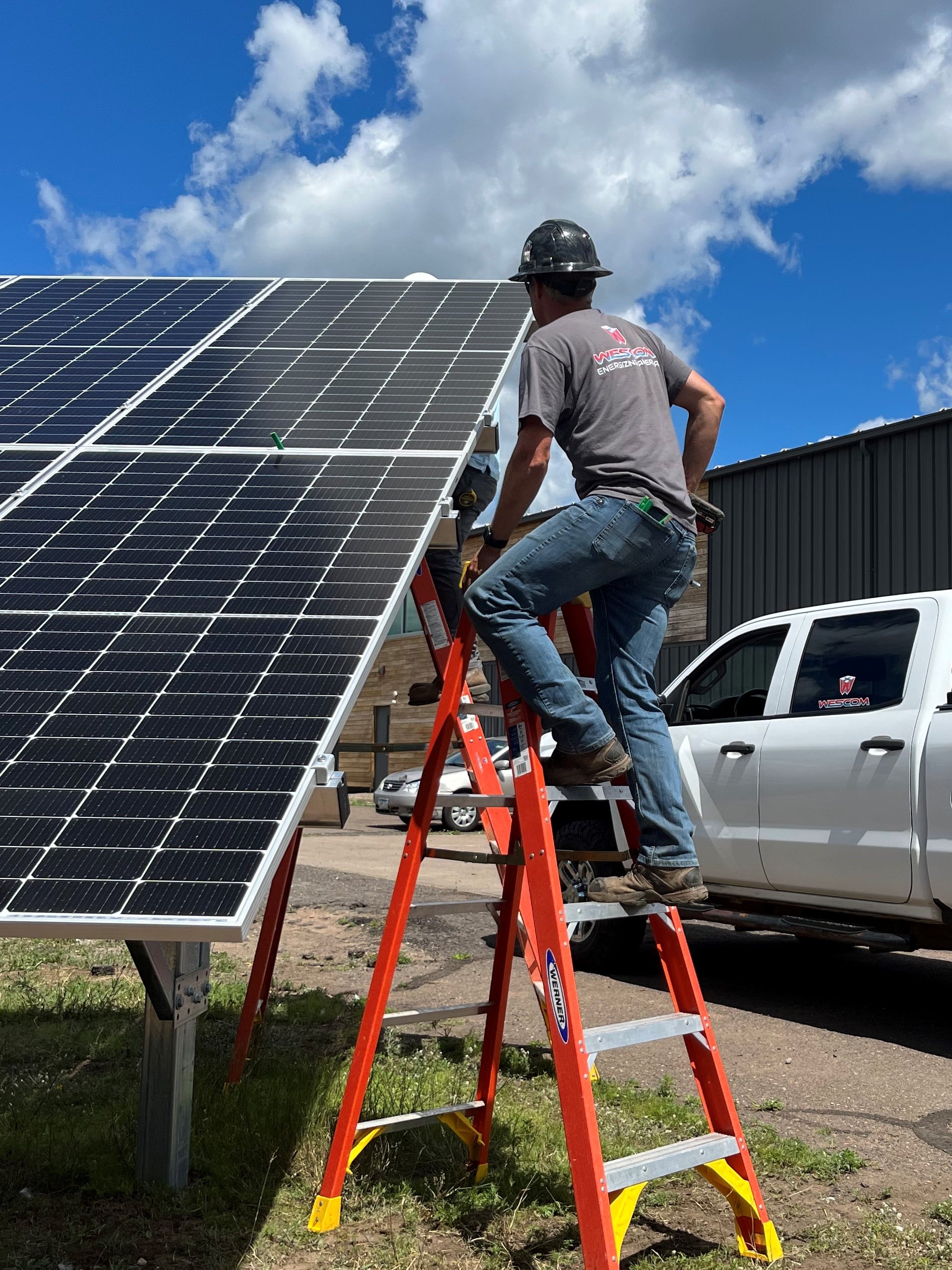 Man standing on ladder while installing solar panels