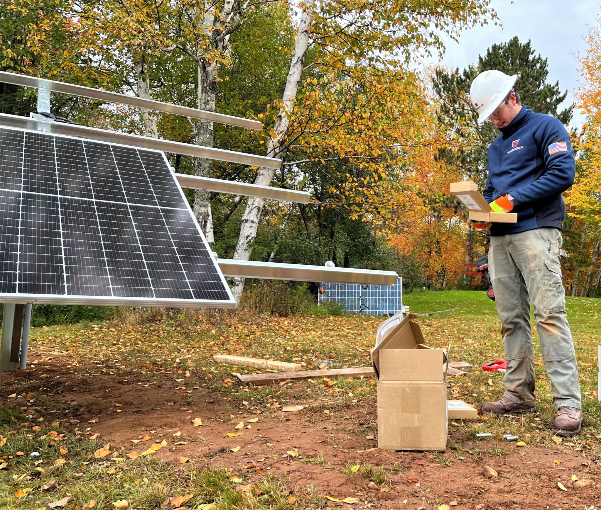 A Wescom employee looking down and grabbing a tool to work on a nicely sized solar array 