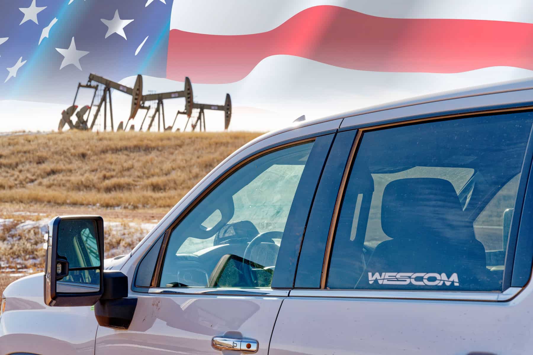 Wescom truck parked in front of oil drills with an American flag in the background